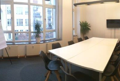 Spacious and bright conference room available for office space rental in Berlin Mitte, featuring a large table, chairs, and a whiteboard.