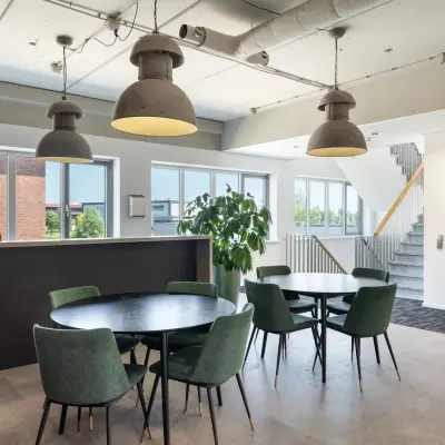 Spacious office to rent at Tolnasingel 1 - 3, Bodegraven featuring modern furnishings with round tables and chairs, surrounded by natural light from large windows.
