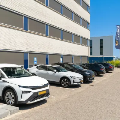 Parking area with several cars in front of an office building at Tolnasingel 1 - 3, Bodegraven, available for office space rental.
