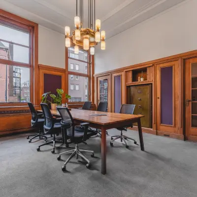 Office space for rent at Ceresstraat 13, Breda Centrum-Station, featuring a furnished meeting room with a large wooden table and chairs, surrounded by wooden paneling and large windows.