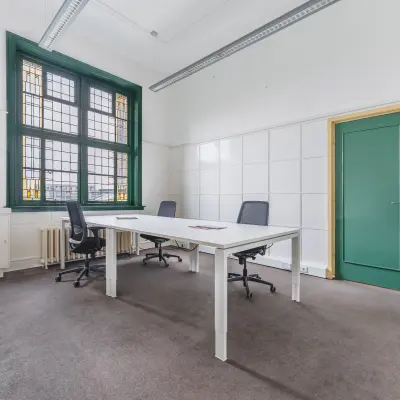 Bright office space with modern furnishings, featuring large windows and a simple, clean design, ideal for office space rental in Breda Centrum-Station.