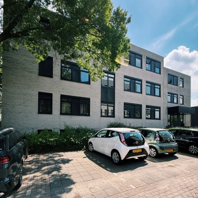 Exterior view of an office building at Druivenstraat 25-31 in Breda Oost, with cars parked in front, ideal for office space rental.