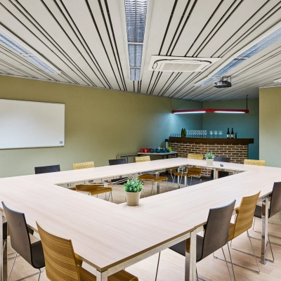 Spacious conference room for office space rental at Leuvensesteenweg 613, featuring U-shaped table setup, chairs, whiteboard, and a small bar area in Brussels Airport.