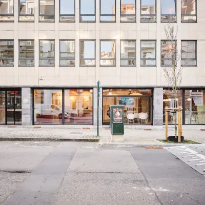 Exterior view of an office building on Rue du Congres 37, featuring large windows with glimpses of the interior, ideal for office space rental in Brussels Center.