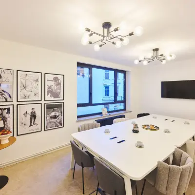 Modern conference room at Rue du Congres 37, Brussels Center, ideal for office space rental, featuring a long table, chairs, and wall art.