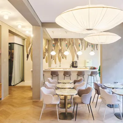 Bright, stylish office space with modern lighting, lounge seating, and a large TV, ideal for renting in Brussels Center.