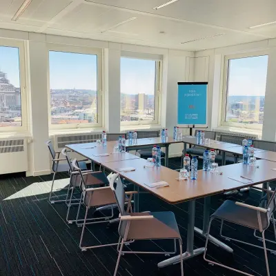 Bright conference room at Rue Joseph Stevens 7 in Brussels Center, ideal for office space rental, featuring large windows with city views, a U-shaped table setup, and multiple chairs.