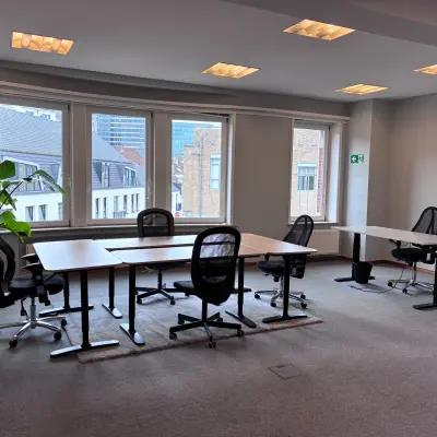 Bright office space with modern desks and chairs, overlooking Brussels European District, available for rent.