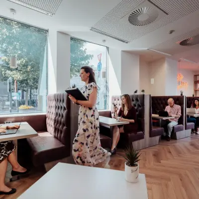 Modern office space in Brussels European District at Robert Schumanplein 2-4 with people working in comfortable booths, ideal for office space rental.