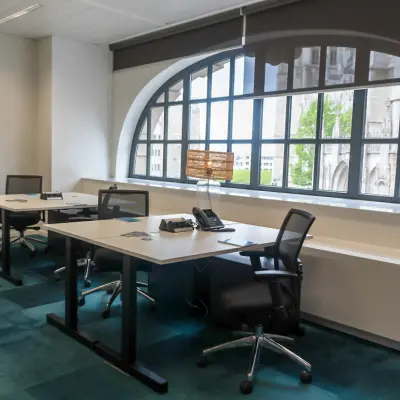 Modern office space rental with large windows and desks located at Rue des Colonies 56, Brussels European District.