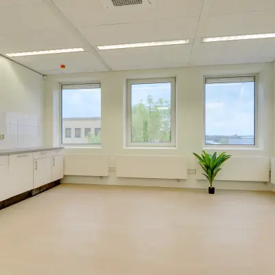 Available office space for rent at Regulierenring 2, Bunnik, featuring large windows and a kitchenette area, ideal for creating a comfortable workspace.