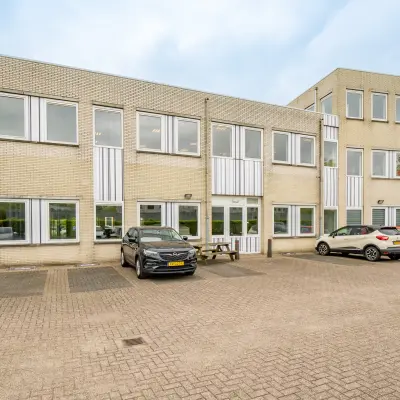 Exterior view of an office building at Regulierenring 2, Bunnik, featuring a parking area with several cars.