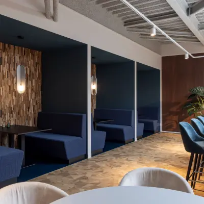 Stylish office lounge with blue booth seating, bar stools, and modern decor at Essebaan 63, Capelle aan den IJssel, ideal for office space rental.