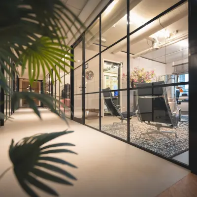 Modern office interior at Rietbaan 2-12 with glass partitions, stylish chairs, and a decorative rug, perfect for office space rental in Capelle aan den IJssel.