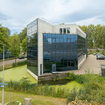 Exterior view of office building at Vlierbaan 20, Capelle aan den IJssel, perfect for office space rental, surrounded by greenery and parking area.