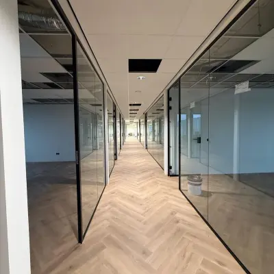 Interior view of unfurnished office space at Vlierbaan 20 in Capelle aan den IJssel, with glass-walled rooms and a wooden floor, ideal for office space rental.