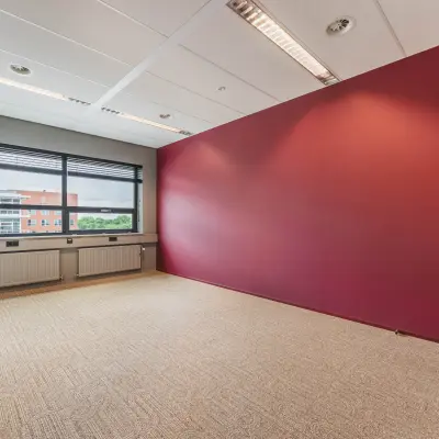 Bright office space at Rijnzathe 12, De Meern, featuring large windows and a vibrant red accent wall, perfect for those looking to rent office space.