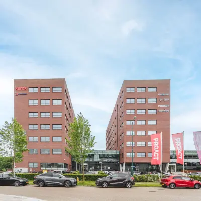 Exterior view of Rijnzathe 12 in De Meern featuring a modern office complex with multiple parked cars in the foreground.