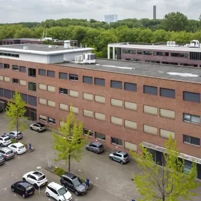 Exterior view of an office building at Delftechpark 9, Delft with an adjacent parking area, ideal for office space rental.