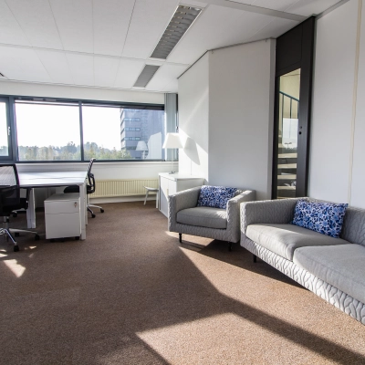 Bright office space at Marshalllaan 2, Delft, featuring a cozy sitting area with sofas and a desk with chairs, available for office space rental.