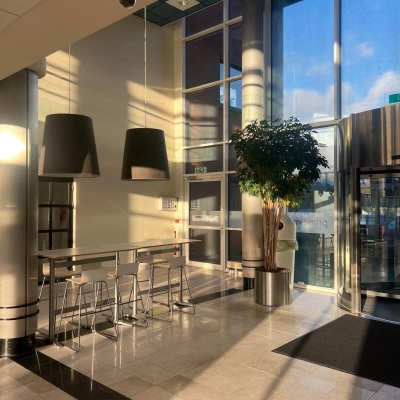 Bright lobby area with tall ceilings and modern lighting at an office to rent in Delft, featuring seating and large windows for natural light.