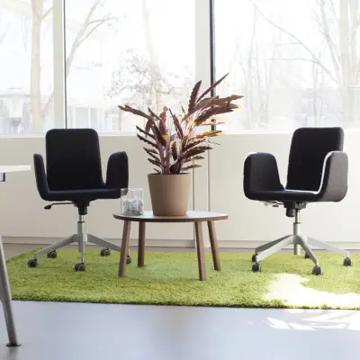 Bright office space at Poortweg 4, Delft, featuring modern seating on a green rug, ideal for meetings. Perfect for office space rental.
