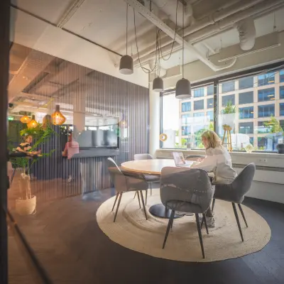 Bright office space at Hambakenwetering 1, Den Bosch, featuring a furnished meeting area with people working on laptops. Perfect for office space rental.