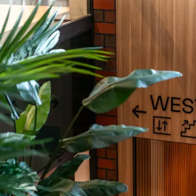 Interior view of Hambakenwetering 5 in Den Bosch, featuring a wooden wall with directional signage and lush green plants, ideal for office space rental.