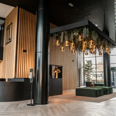 Modern office lobby at Reitschweg 1, Den Bosch, featuring stylish hanging lights and green seating area, available for office space rental.