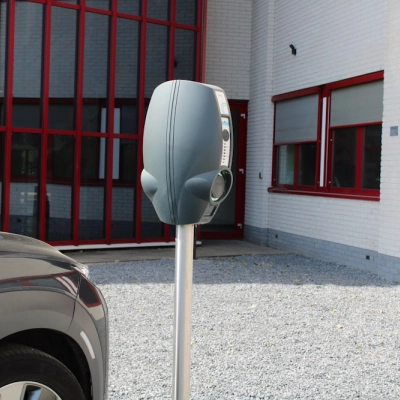 Exterior view of office space for rent at Keulenstraat 1, Deventer, featuring a parking area with an electric vehicle charging station.
