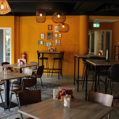 Lively office space for rent at Keulenstraat 10, Deventer, featuring modern furnishings with wooden tables and chairs, warm lighting, and wall decor. Ideal for office space rental.