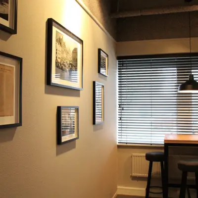 Cozy corner office space at Keulenstraat 12 in Deventer featuring a high table with stools and wall decor, perfect for casual meetings. Ideal for office space rental needs.