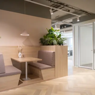 Inviting office space rental at Diemerhof 42, Diemen, featuring a cozy booth with plants and modern lighting for informal meetings.