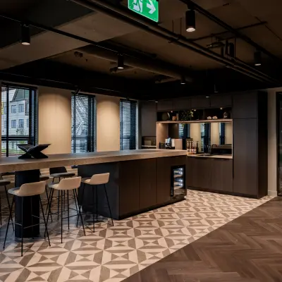 Contemporary office space at Diemerhof 42, Diemen, featuring a stylish pantry area with bar seating and modern lighting, ideal for office space rental.