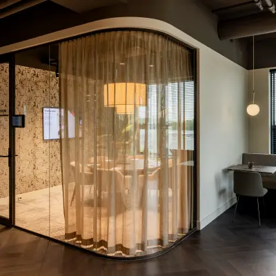 A modern office space at Diemerhof 42, Diemen, featuring a stylish conference room with glass walls and surrounding seating area, ideal for office space rental.