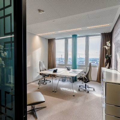 Bright office space rental in Dreischeibenhaus, Düsseldorf Old Town, featuring modern furnishings and large windows with city views, offering an ideal workspace environment.
