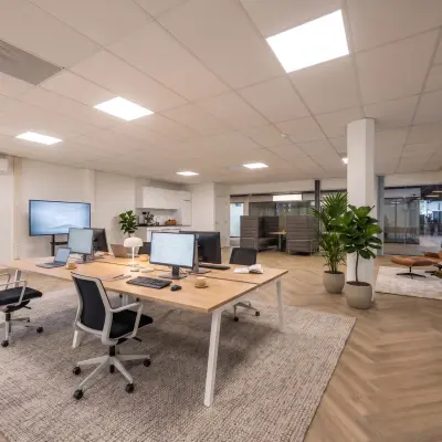 Modern office space at Eindhoven Airport with workstations, computers, and a lounge area, available for rent.