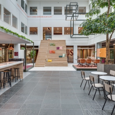 Spacious interior of office space rental at Stadhuisplein 10, Eindhoven Center, featuring seating areas and a staircase with cushions.
