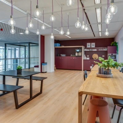 Modern office space rental at Stadhuisplein 10 in Eindhoven Center featuring stylish lighting, tables, and a kitchen area with seating, ideal for breaks or casual meetings.