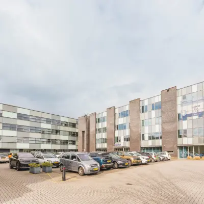 Modern office building at Hurksestraat 60, Eindhoven De Hurk, showcasing glass facades and a spacious parking area.