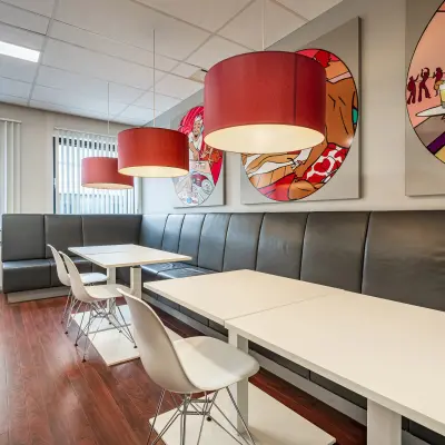 Modern office space in Eindhoven De Hurk featuring artistic wall decor, sleek tables, and contemporary pendant lighting, available for office space rental.