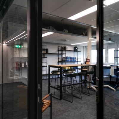 Modern office space featuring glass partitions and high tables, perfect for collaborative work. Located at TU campus, De Zaale 11, in Eindhoven High Tech Campus, this bright space is available for office space rental.