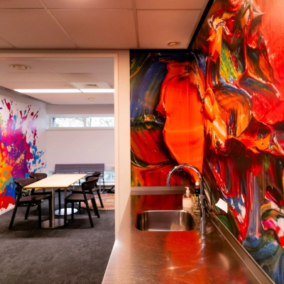 Vibrant interior at TU Campus, De Zaale 11 in Eindhoven, featuring colorful walls and a meeting area, ideal for office space rental. Includes a small kitchenette with a stainless steel counter and sink.
