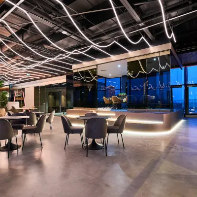 Modern office space with sleek lighting, furnished with round tables and chairs, creating a dynamic environment for renters at Achtseweg Zuid 159R, Eindhoven Strijp-S.