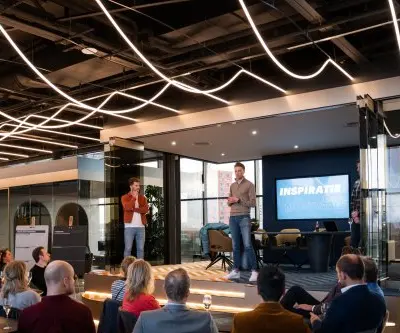 A modern, furnished office space in Eindhoven Strijp-S with people attending a presentation, ideal for office space rental.