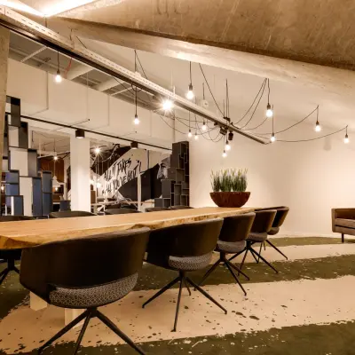 Modern office space at Frederiklaan 10E in Eindhoven Strijp-S with a long wooden table and chairs, suitable for a dynamic workspace environment. Ideal for office space rental.