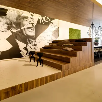 Contemporary office space at Frederiklaan 10E, Eindhoven Strijp-S, featuring wooden tiered seating with cushions and a stylish wall mural, available for office space rental.