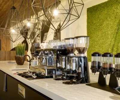 Modern office lounge area at Frederiklaan 10E, Eindhoven Strijp-S, featuring coffee machines and stylish lighting fixtures, ideal for office space rental.