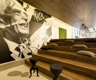 Stylish office space at Frederiklaan 10E, Eindhoven Strijp-S with tiered wooden seating, modern decor, and wall art. Ideal for creative workspace and office space rental.