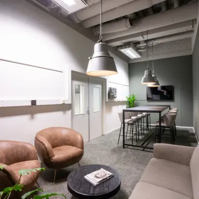 Furnished office space rental at Torenallee 20, Eindhoven Strijp-S, featuring modern seating with bar stools and a TV in a cozy setting.